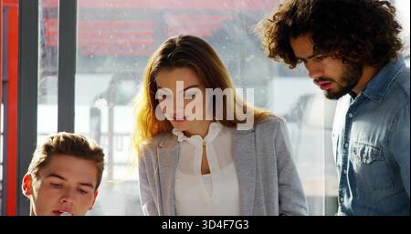 Donna pendente in blazer grigio, uomo in camicia di denim che studia alla finestra dell'ufficio con montatura rossa Foto Stock