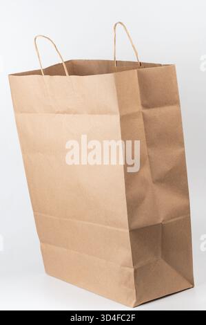 Il sacchetto di carta marrone è in posizione verticale su sfondo bianco, perfetto per lo shopping o per confezionare regali con il suo design robusto. Foto Stock