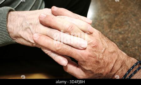 Un uomo e un uomo anziano si tengono per mano. Concetto di aiuto, collaborazione. La scena è calda, confortante e riflette l'amore e la comprensione. Foto Stock
