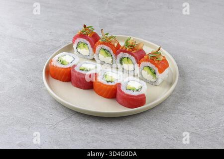 Cibo, sushi all'interno ripieni di avocado cremoso e ricco formaggio spalmabile, conditi con tonno fresco e fette di salmone, rifiniti con zenzero sottaceto Foto Stock
