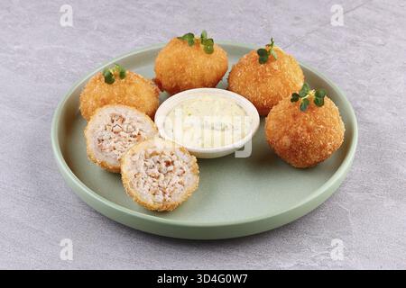 Cibo, crocchette croccanti di pollo e riso con salsa maionese alle erbe cremose su un piatto verde, vista dall'alto, spazio per copiare Foto Stock