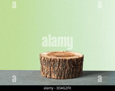 Piccolo ceppo di legno utilizzato come podio naturale su sfondo verde sfumato. Perfetto per prodotti ecologici o display estetico. Foto Stock