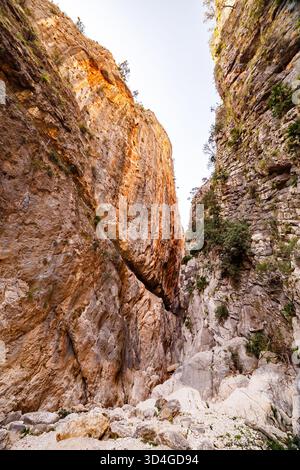 Una spettacolare vista a basso angolo che cattura l'immensa scala dell'ingresso della Gola di Isbert, con torreggianti pareti stratificate del canyon immerse in un caldo e suggestivo Foto Stock