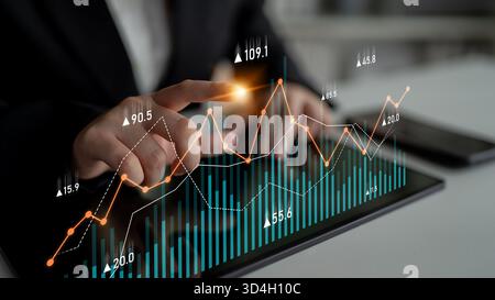 Un professionista aziendale si occupa delle tendenze del mercato azionario su un tablet digitale, mostrando la crescita attraverso l'analisi visiva dei dati in uno spazio di lavoro contemporaneo Foto Stock