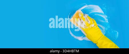 Il guanto giallo contiene spugna e salviette schiuma di sapone su sfondo blu Foto Stock