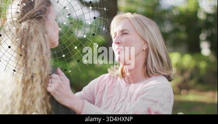 Donna parlante in maglione rosa che mette le mani sulle spalle del compagno in giardino, con velo a rete Foto Stock