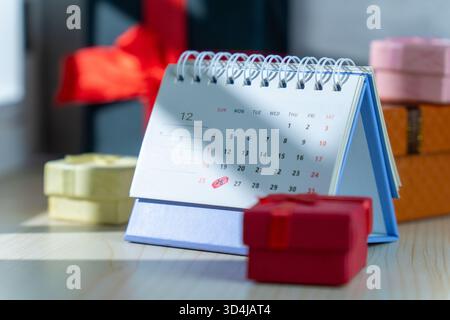 Il calendario della scrivania di dicembre che mette in evidenza Natale e Santo Stefano è circondato da colorate confezioni regalo di varie dimensioni, che simboleggiano le vendite natalizie Foto Stock