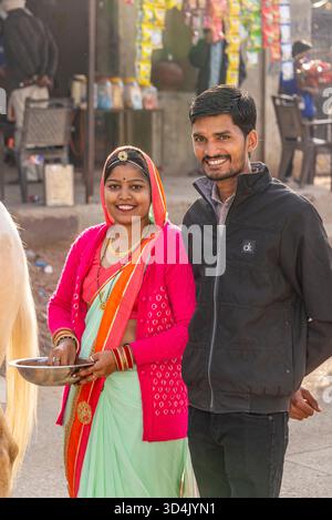 Donna in tradizionale Saree e uomo sorridente nella vivace scena del mercato indiano. Pushkar, India, 24 gennaio 2024 Foto Stock