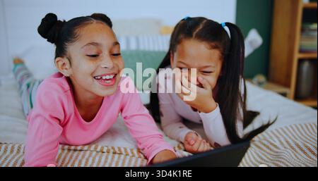 Rilassati, ridi e i bambini sul tablet in camera da letto per l'intrattenimento online, guardare cartoni animati e film. Casa di famiglia, fratelli e ragazze felici su tecnologia per Foto Stock