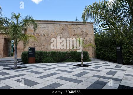 Rilievo a parete in pietra nel moderno cortile con palme Foto Stock