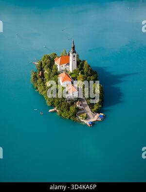 Veduta aerea dell'iconica chiesa che sorge orgogliosamente sull'isola di Bled circondata dal lago turchese, un gioiello immerso nel verde lussureggiante, Bled, Radovljica, Slo Foto Stock