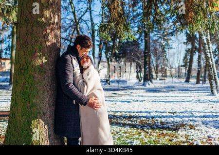 Una coppia elegante che ama passeggiare nel parco invernale. Uomo e donna che indossano cappotti caldi nelle giornate soleggiate e innevate Foto Stock