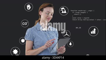 Tocca la donna che indossa una camicia a righe utilizzando un tablet in studio, mostrando icone di dati e codice Foto Stock