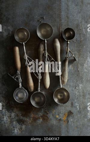Fotografia di alta qualità di gelati vintage assortiti con patina e manici in legno, con stile sopra la testa su uno sfondo rustico in metallo: Idea Foto Stock