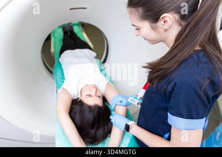 Il tecnico di scansione TC si affaccia sul paziente nello scanner di tomografia computerizzata durante la preparazione della procedura. Paziente donna che entra nello scanner TC. Foto Stock