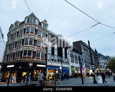 Manchester, Regno Unito - 30 settembre 2025: Una vivace scena cittadina di Manchester con un negozio Starbucks, diversi pedoni e un'architettura sorprendente. Foto Stock