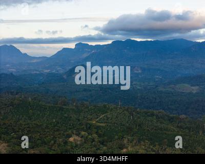 Una vasta distesa di verdi montagne si estende sotto il cielo nuvoloso, mostrando la bellezza della natura al crepuscolo. Foto Stock