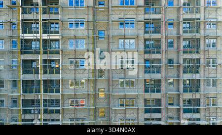Facciata di un edificio residenziale in fase di ristrutturazione con impalcature e finestre, architettura moderna e lavori in corso Foto Stock