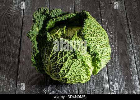 cavolo savoy su sfondo di legno nero Foto Stock