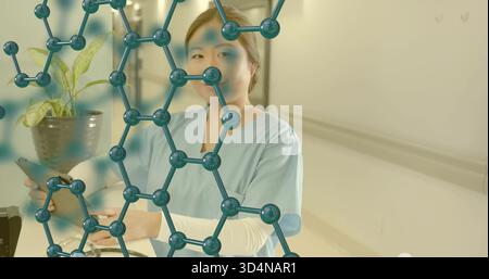Tenendo la compressa, l'infermiere in scrub blu si trova presso la stazione infermieristica, con stetoscopio, sovrapposizione molecolare Foto Stock