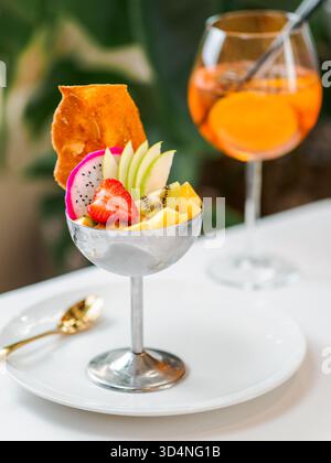 Sorbetto del Paradiso tropicale con pompelmo, mango, frutto della passione decorato con frutta fresca e croccanti biscotti di tuile. Gelato tropicale in una ciotola di metallo. Primo piano del dessert Tropical Fruit Cup Foto Stock
