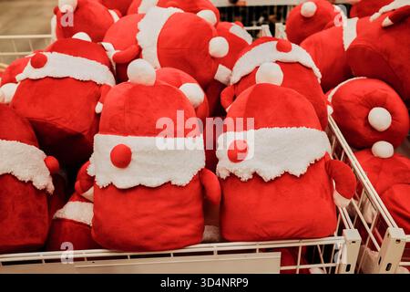 Una pila di morbidi giocattoli rossi a tema Babbo Natale disposti in un cestino. Il concetto riflette calore, allegria e gioia delle vacanze. Foto Stock