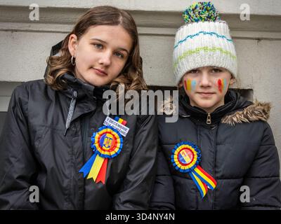 Due bambini con nastri rumeni e facciate dipinte per celebrare la giornata nazionale nel centro di Bacău. Foto Stock