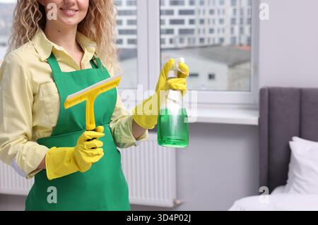 Finestra di pulizia. Donna con spatola e detergente in casa, primo piano. Spazio per il testo Foto Stock