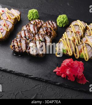 Cibo, set di sushi al forno con wasabi e zenzero su nero Foto Stock