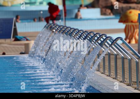 Moderno centro benessere con acqua a cascata in una piscina blu. Foto Stock