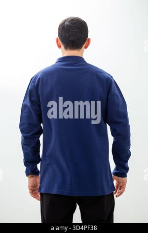 Vista posteriore dell'uomo in una polo a manica lunga blu navy su sfondo bianco studio. Foto Stock