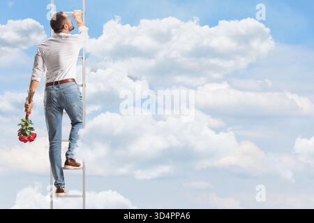 Ripresa posteriore di un uomo che sale una scala nel cielo e tiene in mano rose rosse Foto Stock