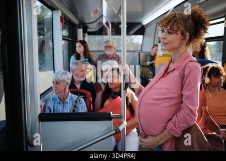 Donna incinta che viaggia in autobus urbano Foto Stock