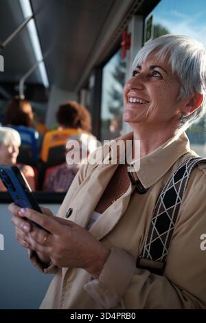Donna anziana che viaggia in autobus utilizzando lo smartphone Foto Stock