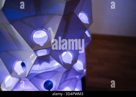 Primo piano della futuristica torre idroponica verticale caratterizzata da luci blu, una struttura geometrica illuminante che mette in risalto l'innovativa agricoltura interna Foto Stock