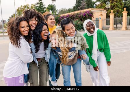 Donne felici e diverse che ridono insieme in città Foto Stock