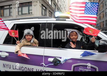 New York, Stati Uniti. 11 novembre 2025. I partecipanti alla sfilata sventolano bandiere americane e bandiere del corpo dei Marines mentre guidano un veicolo alla parata dei Veterans Day di New York City a Manhattan, New York City. La parata annuale che commemora i membri dell'esercito degli Stati Uniti attira veterani, militari in servizio attivo, bande marcianti e rivelatori nel centro di Manhattan. Quest'anno, la parata celebra il 250° anniversario dell'esercito degli Stati Uniti. Credito: SOPA Images Limited/Alamy Live News Foto Stock
