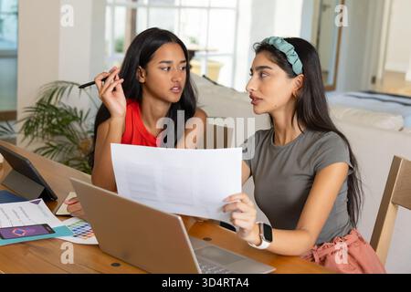 Discussione di idee di design diverse colleghe si incontrano al tavolo dell'ufficio domestico, con un notebook Foto Stock