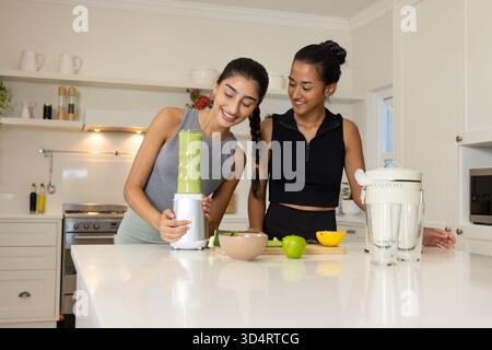 Frullare diverse amiche per preparare frullati in una moderna cucina casalinga, con frullatore da banco Foto Stock