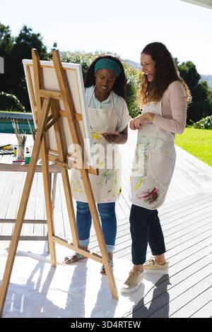 Dipingere diverse istruttrici e studentesse al cavalletto in legno sul ponte della piscina, con tavolozza di pittura Foto Stock