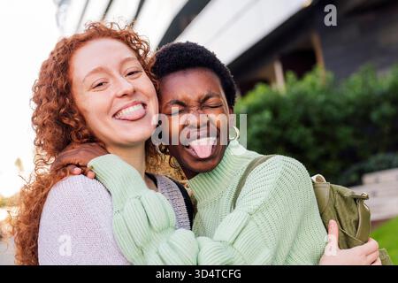 due giovani donne che abbracciano e tirano fuori la lingua Foto Stock
