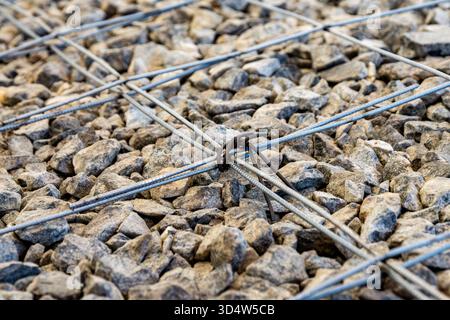 Dettaglio della griglia per armature in acciaio scanalato legata con filo su fondo di ghiaia pronta per il versamento di calcestruzzo, messa a fuoco selettiva Foto Stock