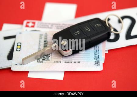 Targa Svizzera e chiave di accensione sulla bandiera svizzera primo piano. Patente di guida e concetto di immatricolazione Foto Stock