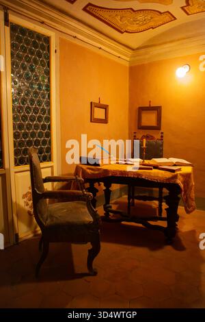 Antico studio con tavolo in legno, libri a lume di candela e sedie in velluto in una calda atmosfera classica. Foto Stock