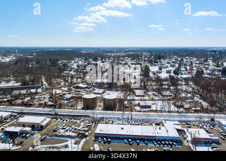 Vista aerea della città innevata con case residenziali grandi serbatoi di stoccaggio sotto il cielo azzurro limpido il giorno d'inverno Foto Stock