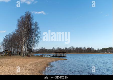 Rilassante scenario lacustre a Valdemarpils, Lettonia, con una spiaggia sabbiosa e un molo in legno. Foto Stock