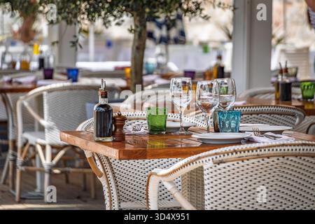 Tavoli all'aperto che aspettano i clienti in un ristorante sulla spiaggia all'aperto sul lungomare a Nizza, nel sud della Francia Foto Stock