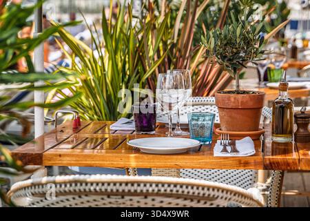 Tavoli all'aperto che aspettano i clienti in un ristorante sulla spiaggia all'aperto sul lungomare a Nizza, nel sud della Francia Foto Stock