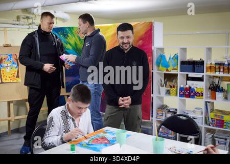 Kherson City, Ucraina. 11 novembre 2025. Il presidente ucraino Volodymyr Zelenskyy, a destra, guarda i bambini prendere parte a una lezione di pittura durante una visita a un centro per bambini costruito all'interno di un bunker, 11 novembre 2025, a Kherson City, Ucraina. Zelensky visitò la città in rovina nel terzo anniversario della liberazione dal controllo russo. Credito: Presidenza Ucraina/Ufficio stampa presidenziale ucraino/Alamy Live News Foto Stock