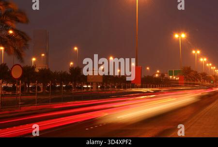 Strada urbana in città di notte con vivaci percorsi di luci per auto dai colori vivaci Foto Stock